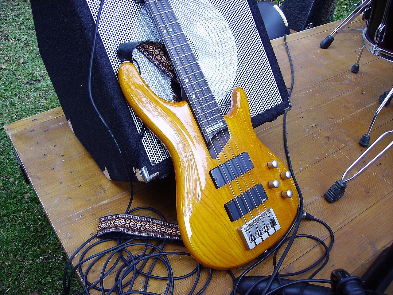 Natural wood custom bass guitar against an amplifier