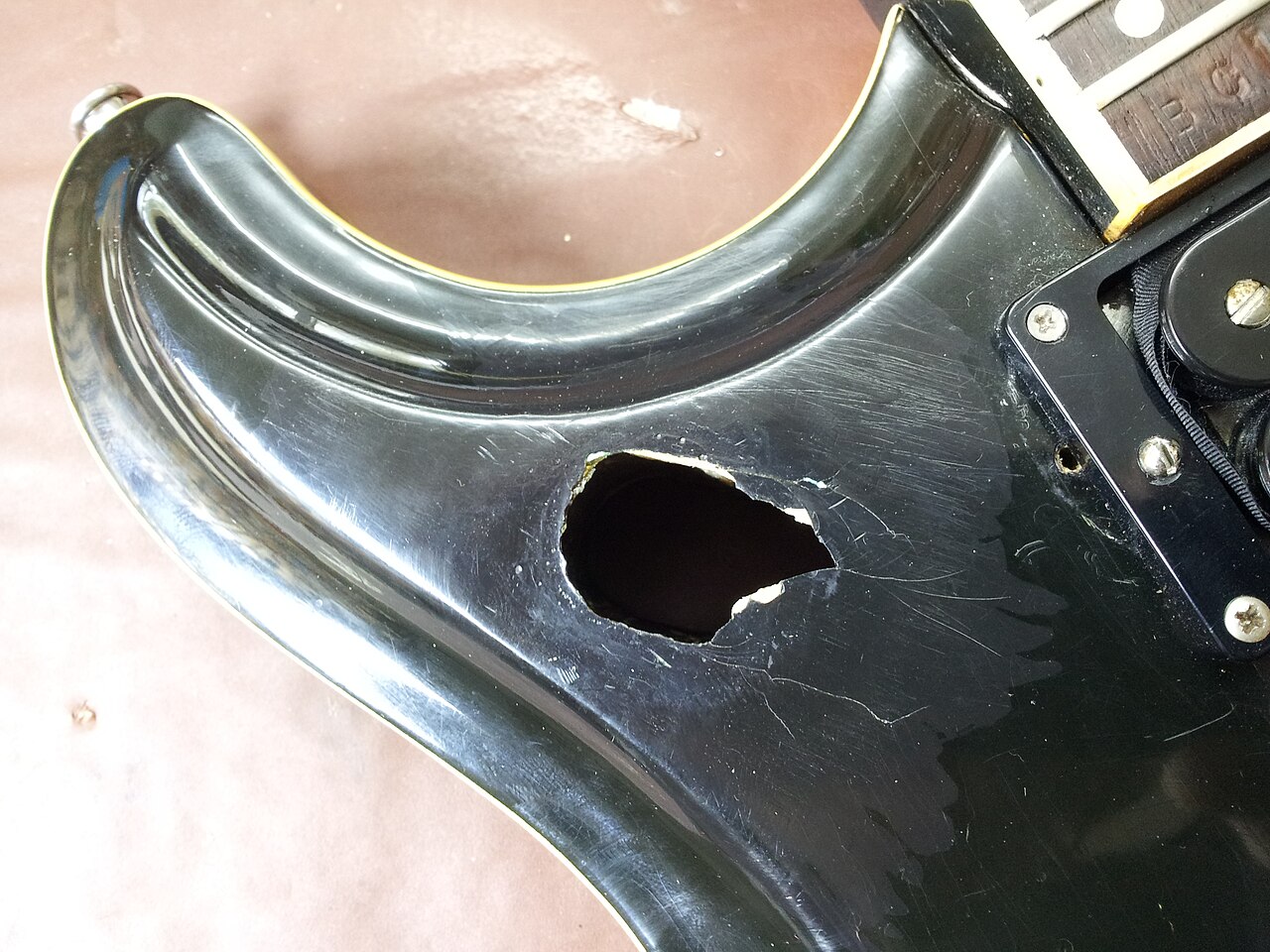 Damaged electric guitar body near the neck joint awaiting repair